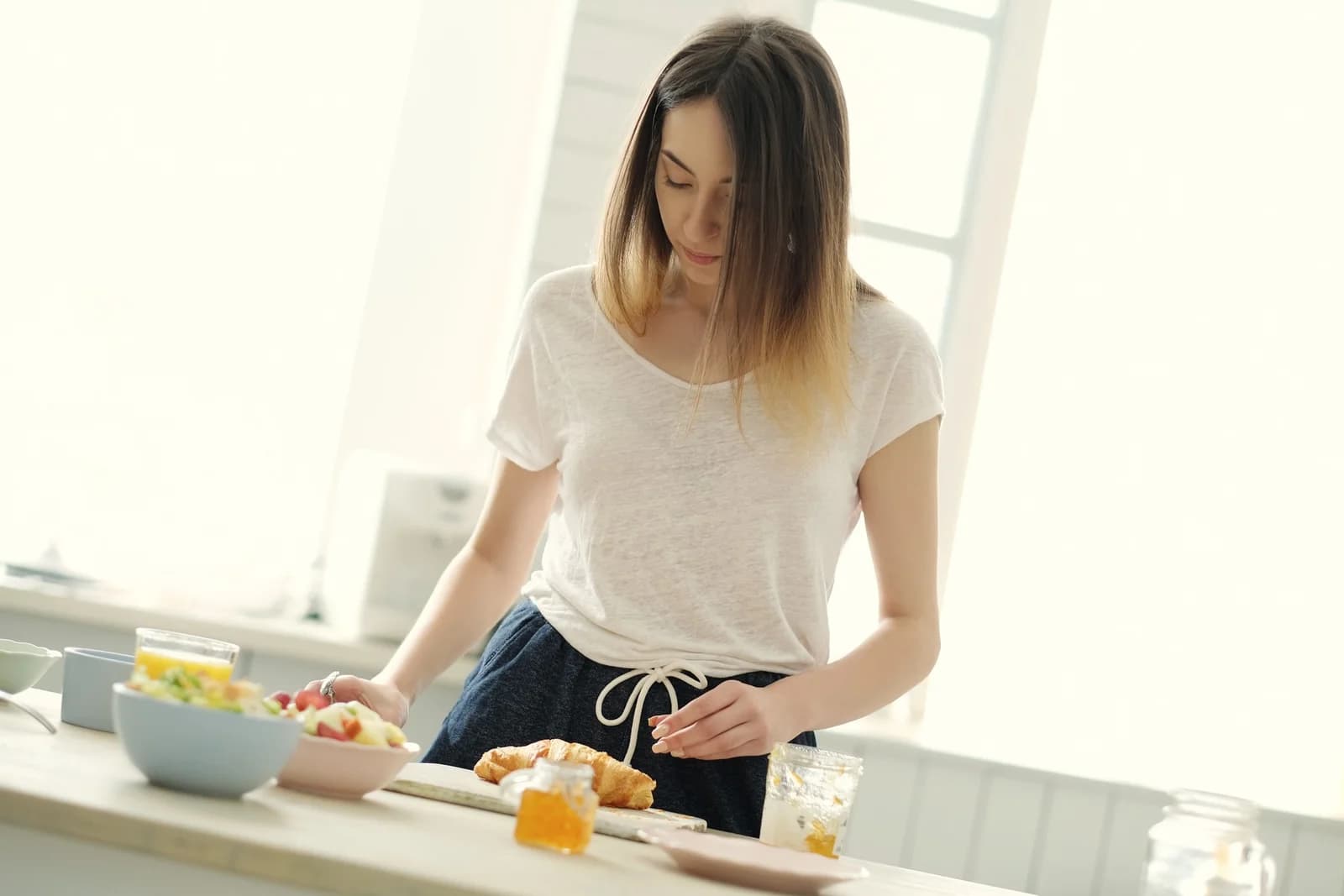 Mulher preparando o café da manhã na cozinha, ilustrando conteúdo sobre alimentação e glicemia.