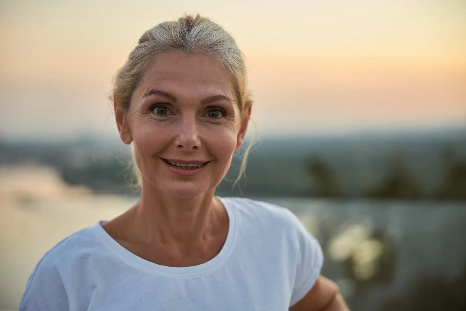 Mulher madura sorrindo ao entardecer, ilustrando conteúdo sobre menopausa e ganho de peso.