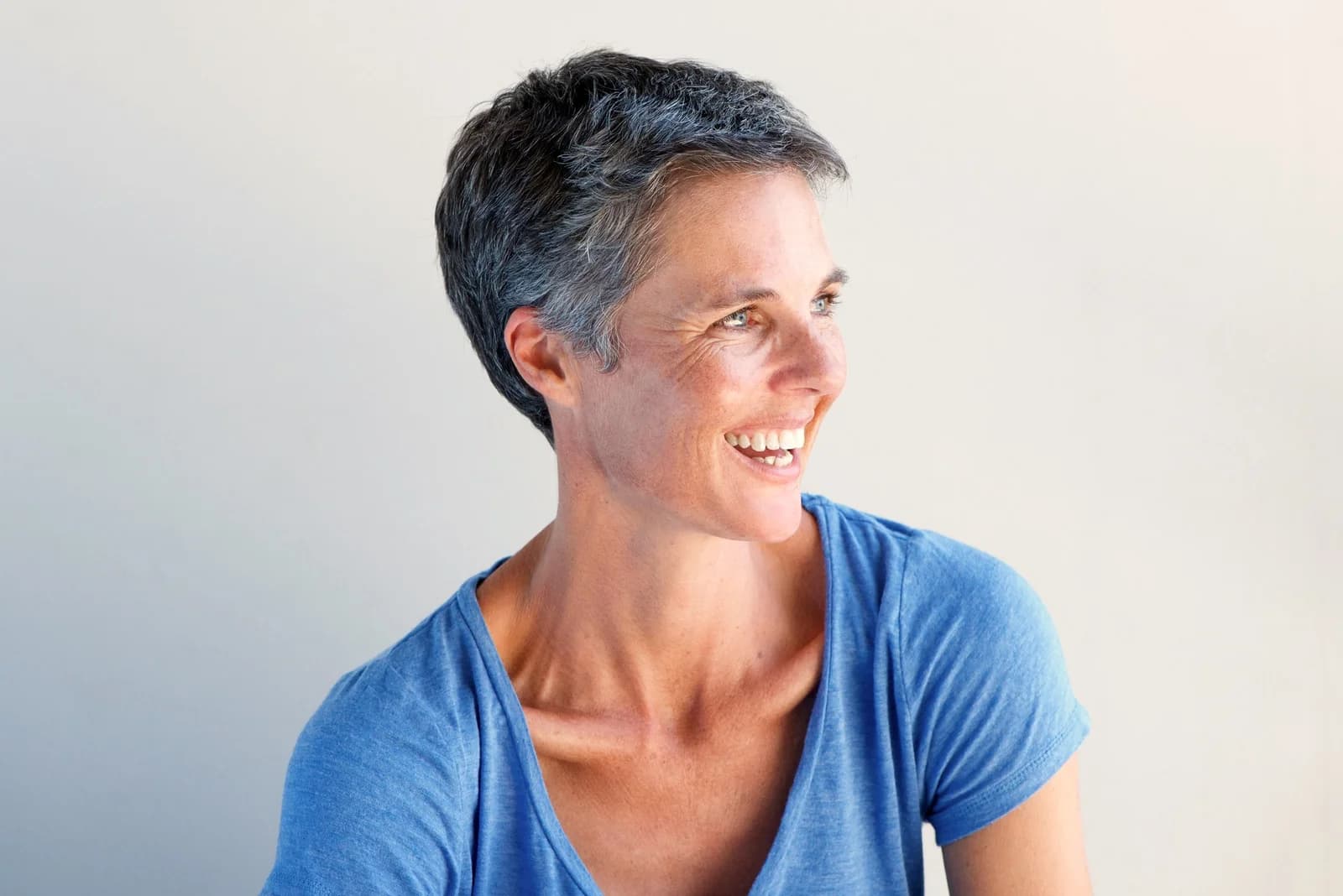 Mulher madura sorrindo em luz natural, ilustrando conteúdo sobre reposição hormonal e peso na menopausa.