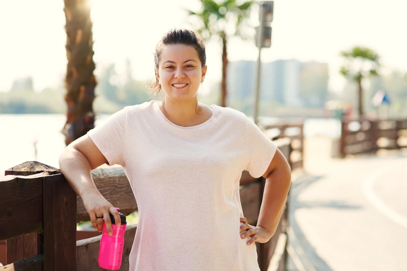 Mulher sorrindo numa pausa do exercício ao ar livre, à beira d'água