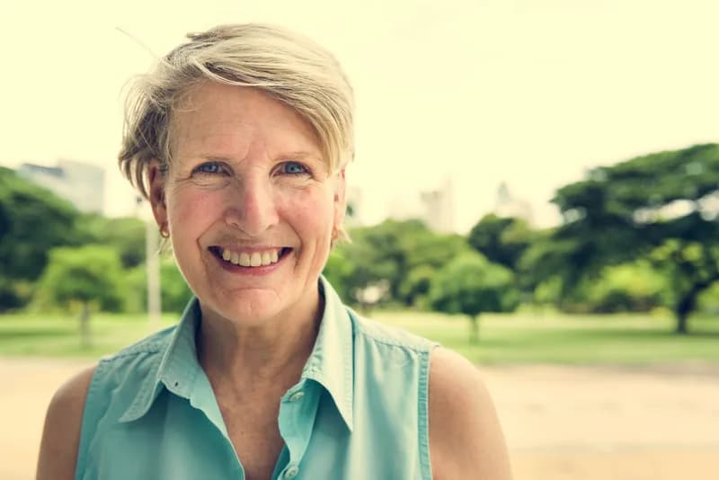 Mulher madura em um parque, ilustrando conteúdo sobre menopausa e osteoporose.