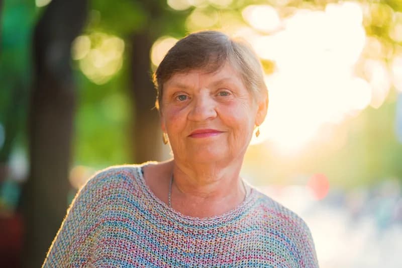 Mulher madura sorrindo ao ar livre, ilustrando conteúdo sobre a menopausa como fase natural que merece cuidado.