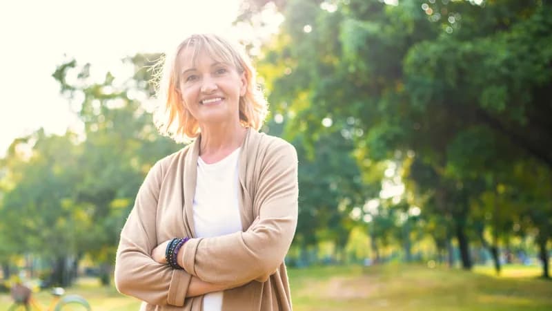 Mulher madura em luz natural, em tom sóbrio, ilustrando conteúdo sobre os sintomas da menopausa.