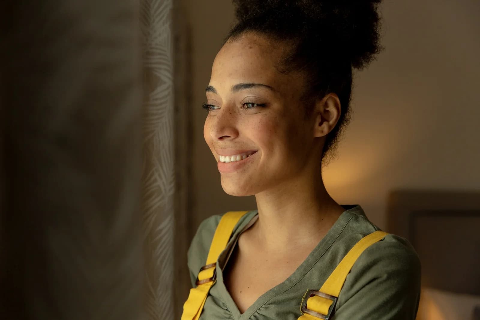 Mulher jovem sorrindo perto da janela, ilustrando conteúdo sobre SOP e gravidez.